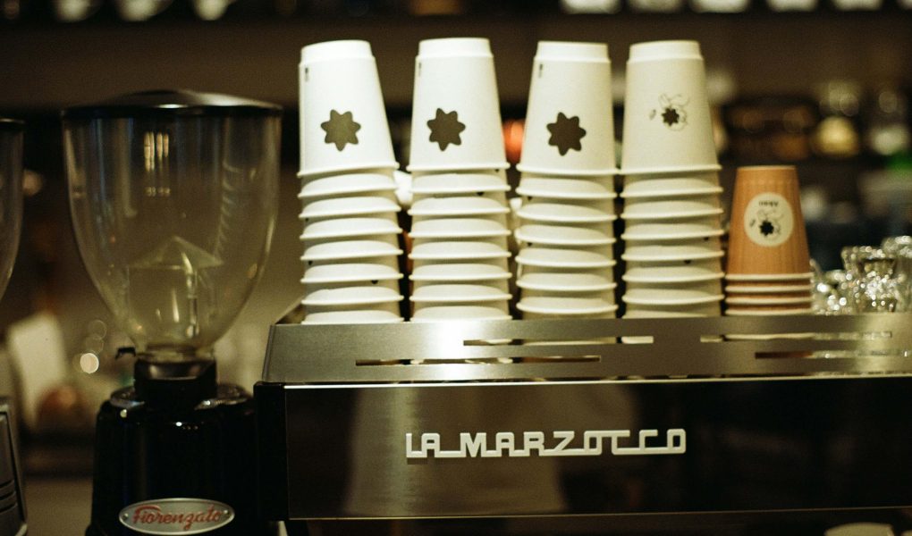 Alcuni bicchieri di plastica bianca e una macchina per il caffè